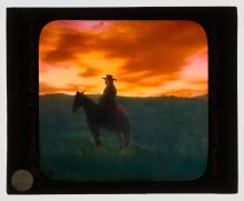 Silhouette of man on horseback with sunset in background.