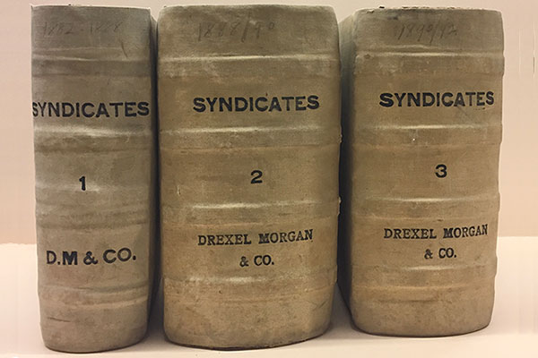 Three thick volumes standing upright with text that syas Syndicates and Drexel Morgan on the spines.