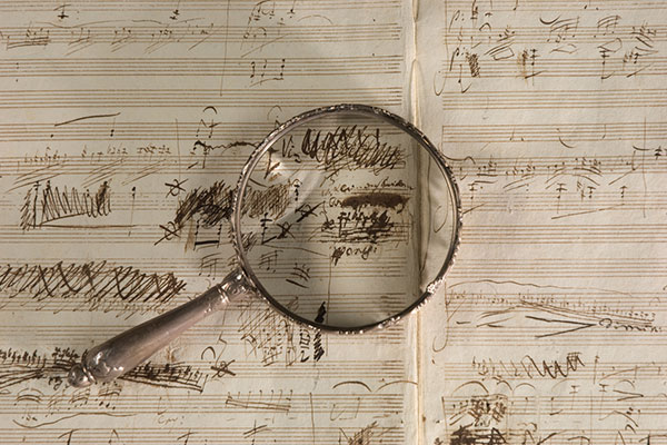 Magnifying glass laying on top of handwritten music manuscript.