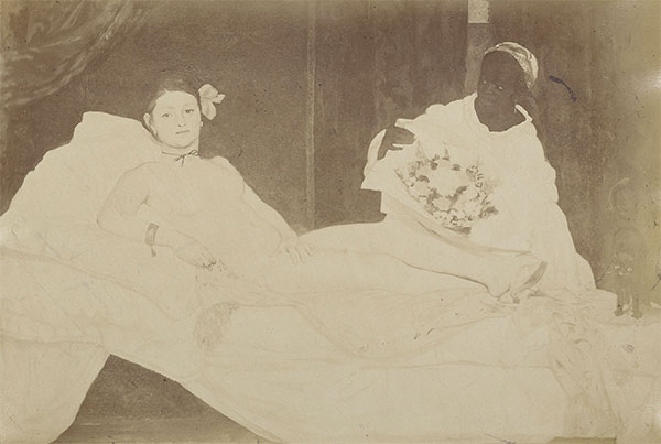 Sepia toned photograph of manet's Olympia depicting a reclined femaile nude and a clothed femaile figure to the right.