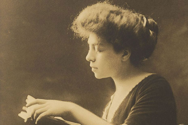 Sepia toned photograph of Belle da Costa Greene holding a book reading it.