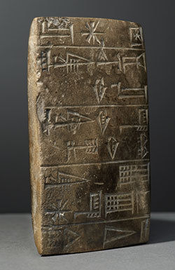 Rectangular grayish brown stone tablet with markings on it.