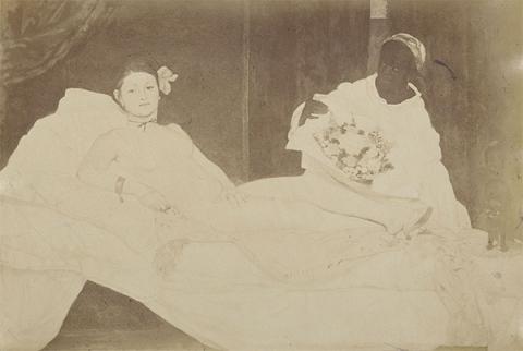 Sepia toned photograph of manet's Olympia depicting a reclined femaile nude and a clothed femaile figure to the right.