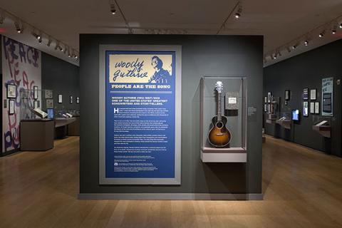 Photo of gallery showing wall panel yellow on blue graphics, wooden floor and dark blue-gray walls.