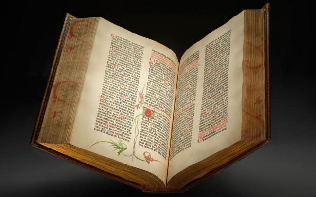 An open Gutenberg Bible photographed on a dark background.