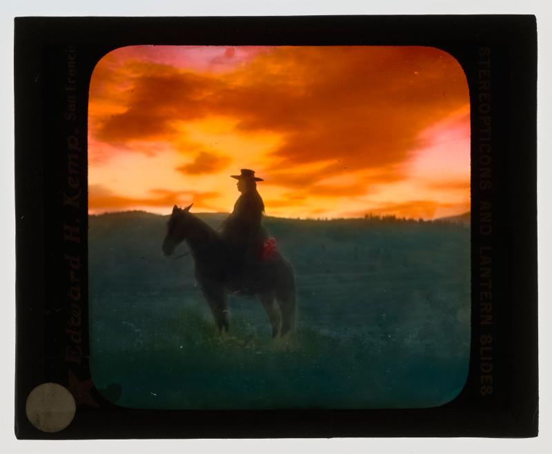 Silhouette of man on horseback with sunset in background.