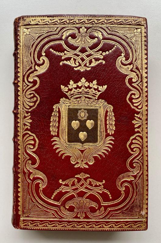 Red leather book binding with gold decoration and coat of arms in the middle.