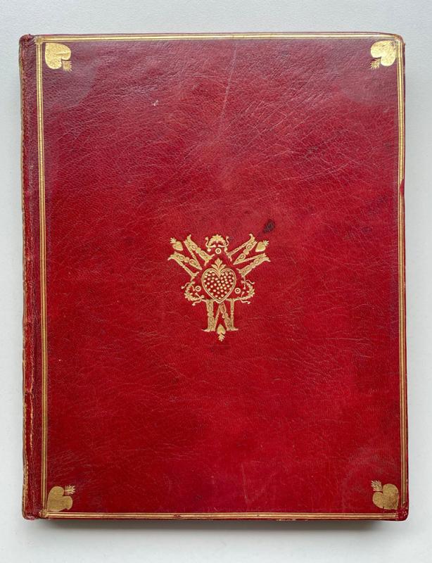 Red leather book binding with gold design in the middle of three M's around a heart.