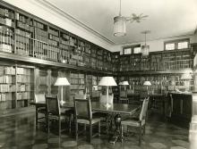 View of Reading Room showing floor to ceiling book shelves, tables and chairs.