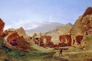 Landscape of a circular wall surrounding arched ruins with mountains and blue sky in background and lone figure in foreground.