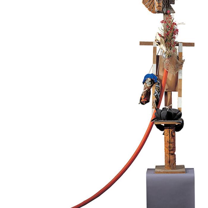 A  stylized figure sculpture made from various found objects and carved wood.