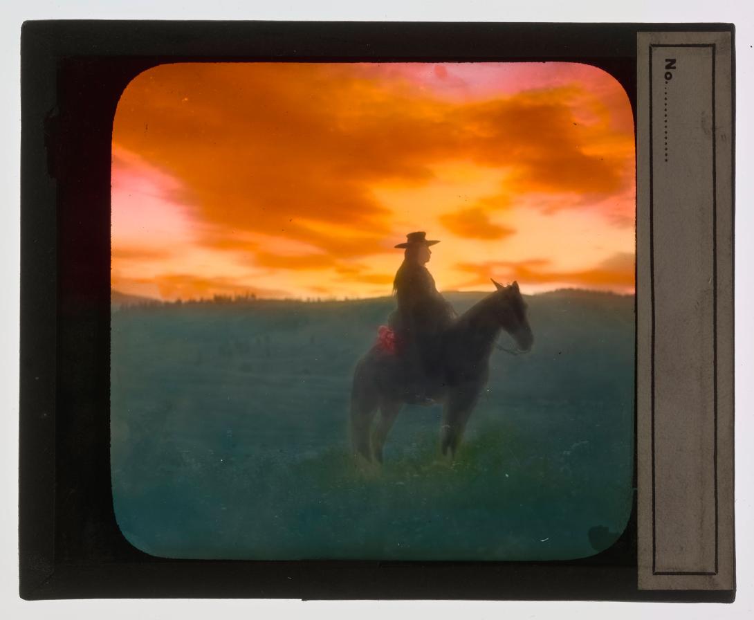 Silhouette of man on horseback with sunset in background.