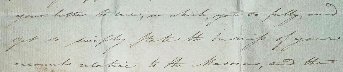 A close-up of an old document featuring handwritten cursive text in brown ink on aged, light brown paper. The script is dense and fills most of the frame.
